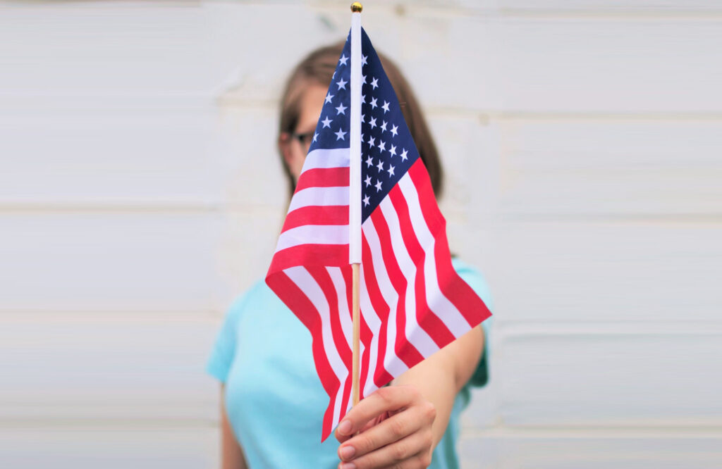 Woman obscured by the US flag she is holding