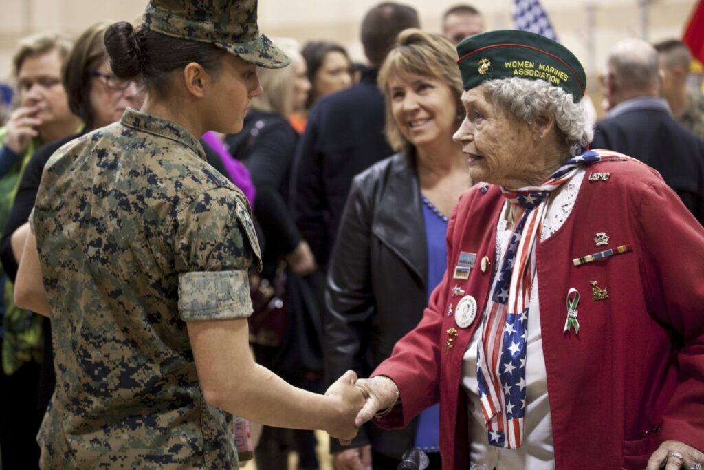 Pfc Maria Daume, US Marine, shaking hands with a retired Marine Corps Woman Veteran.